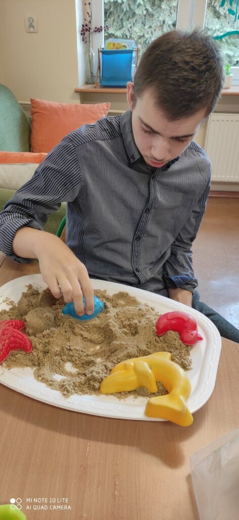 uczeń bawi się piaskiem